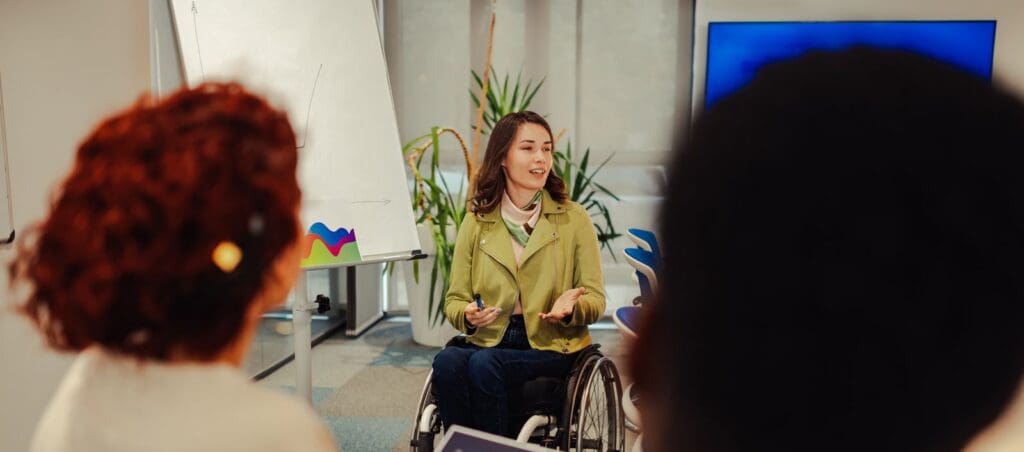 woman in wheelchair in front of a graph giving a talk to an audience